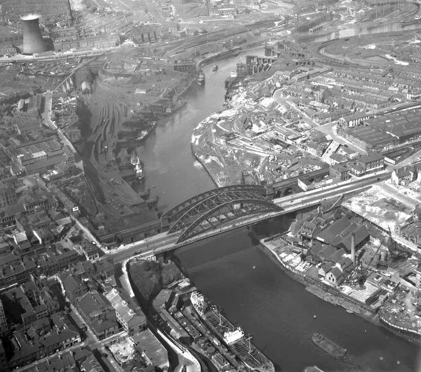 Aerial view of Wearmouth Bridge crossing the River Wear, with ships at the quays, railway sidings and rows of terraced streets.
